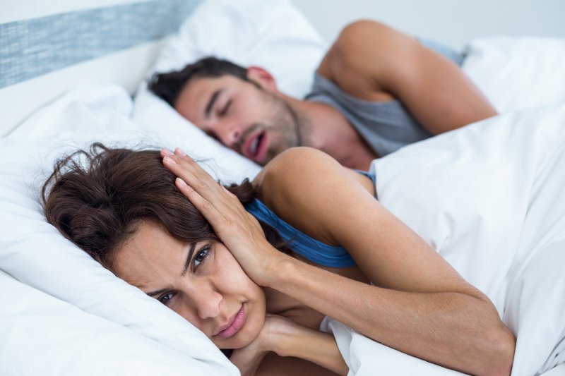 woman in bed next to snoring man 