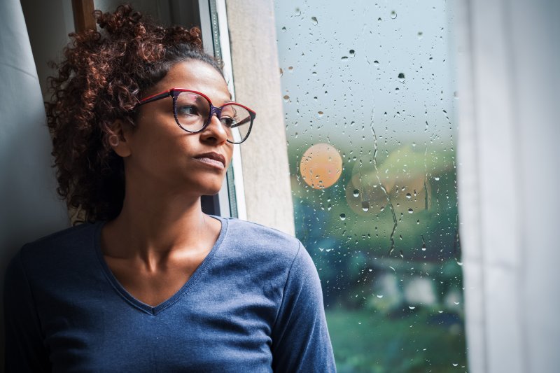 depressed woman looking out a rainy window 