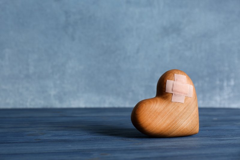 a wooden heart with a band-aid on it 