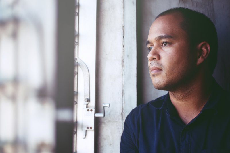 depressed man with sleep apnea looking out window 