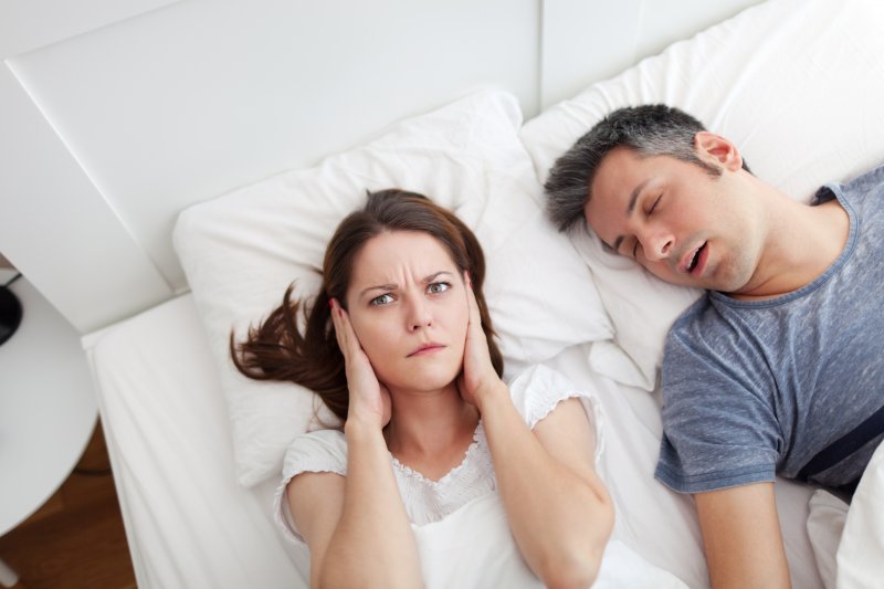man snoring next to young woman 