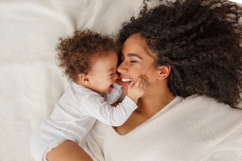 young mother smiling in bed with baby 