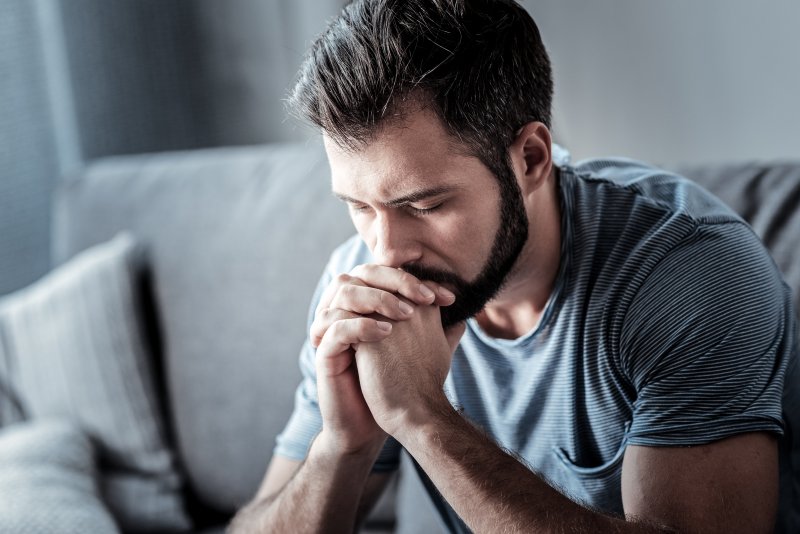 a depressed man sitting tiredly on the couch