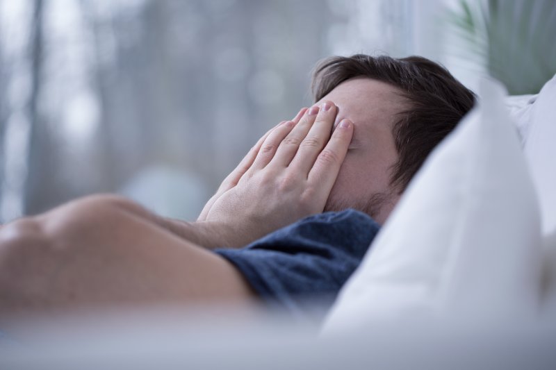 a person covering their eyes due to trouble sleeping