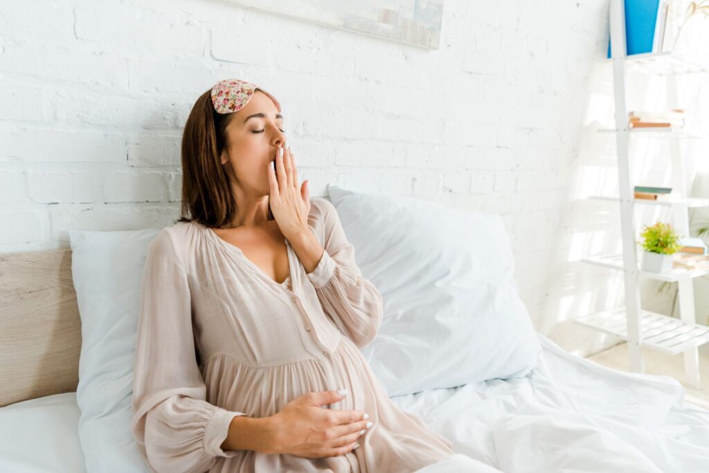 A pregnant woman sitting in a bed.