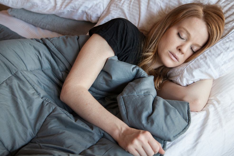 A woman sleeping under a weighted blanket.