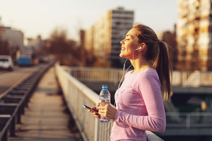 Woman with phone and water bottle jogging through city