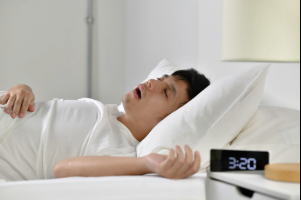 Young man snoring in bed due to sleep apnea