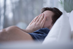 Man sitting on bed looking concerned